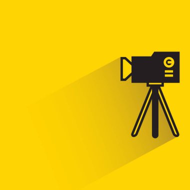 camera on tripod with shadow on yellow background