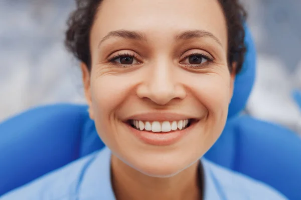 Closeup view of happy woman with healthy teeth smiling at camera in dental chair