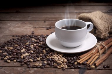 Kahve fincanı ve çay tabağı ahşap bir masada. Koyu arkaplan.