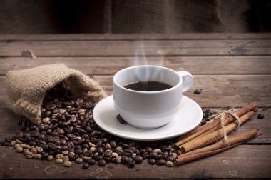 Kahve fincanı ve çay tabağı ahşap bir masada. Koyu arkaplan.