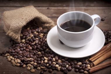 Kahve fincanı ve çay tabağı ahşap bir masada. Koyu arkaplan.