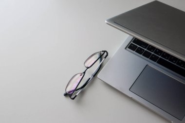 Evde bilgisayarlı ve gözlüklü bir iş yeri. Minimalizm üst görünüm düz masada yatıyordu