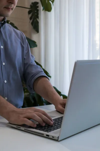 Zbliżenie młodego człowieka pracującego na laptopie. Praca z wnętrza domu minimalizm — Zdjęcie stockowe