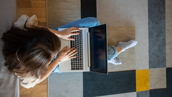 Banner of view from above of woman working on a laptop while sitting on the floor. A young girl is programming