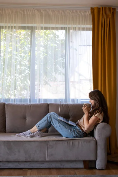 A young woman is drinking a cup of coffee during working from home. — Stock Photo, Image