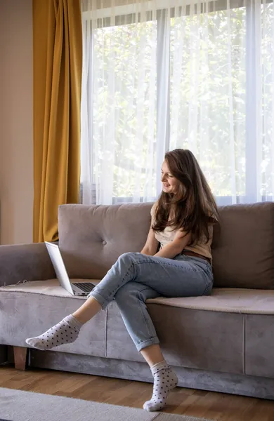 A young woman is doing online shopping remotely. Comfortable cozy apartment. — Stock Photo, Image