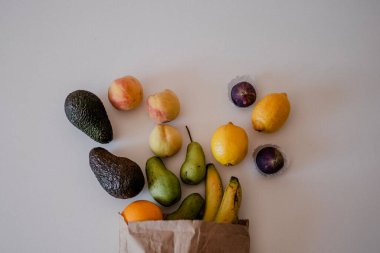 Masadaki el yapımı kese kağıdındaki farklı meyveler. Fotokopi alanı olan sağlıklı bir daire. Avokado, limon, şeftali, armut, portakal.