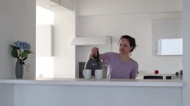 Genç bir kadın mutfakta iki kişilik çay yapıyor.