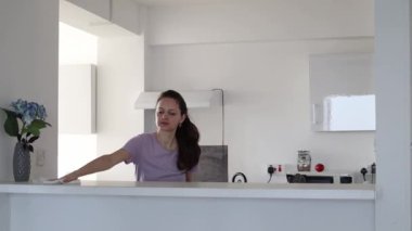 Genç bir kadın evde mutfak yüzeyini temizliyor.