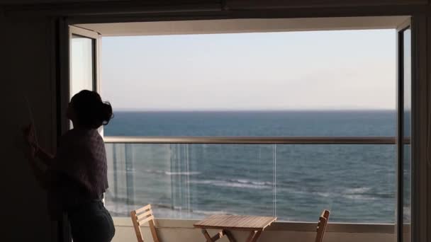 Bir Kadın Deniz Manzaralı Terasın Pencerelerini Açıyor — Stok video