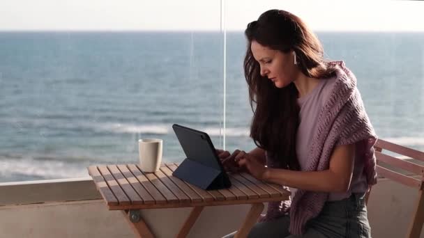 Seorang Wanita Muda Dengan Headphone Bekerja Pada Sebuah Tablet Balkon — Stok Video