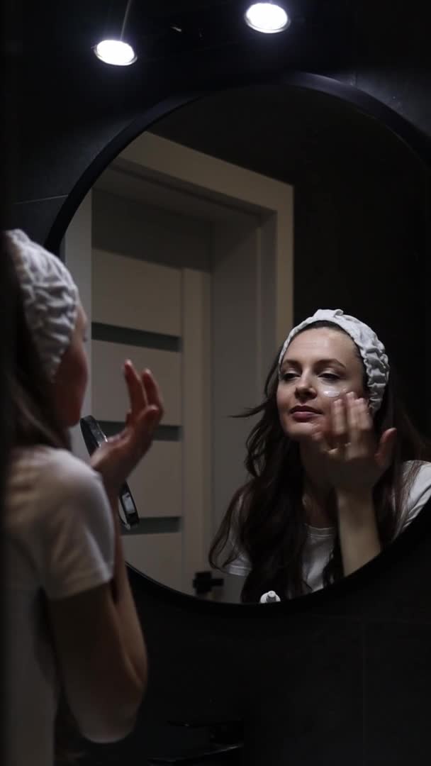 头带应用面部润肤霜的妇女慢动作垂直镜头 — 图库视频影像