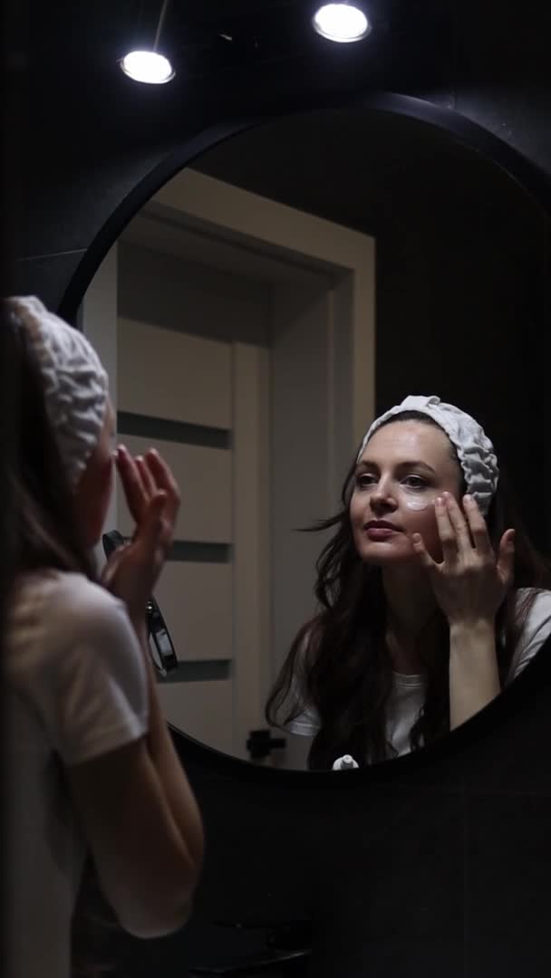 Pionowe wideo młodej kobiety w opasce z kremem nawilżającym do twarzy — Wideo stockowe
