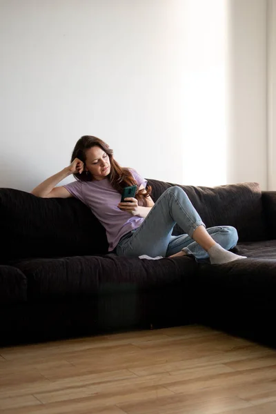 Uttråkad Kvinna Använder Sin Telefon Vardagsrummet Morgonen — Stockfoto