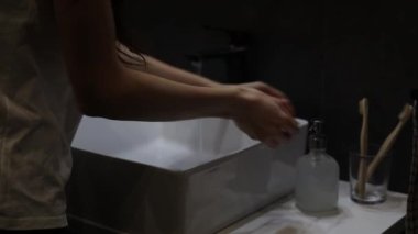 Çağdaş bir apartman dairesinde ellerini sıvı sabunla yıkayan bir kadın.