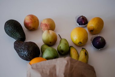 Masadaki el yapımı kese kağıdındaki farklı meyveler. Fotokopi alanı olan sağlıklı bir daire. Avokado, limon, şeftali, armut, portakal.