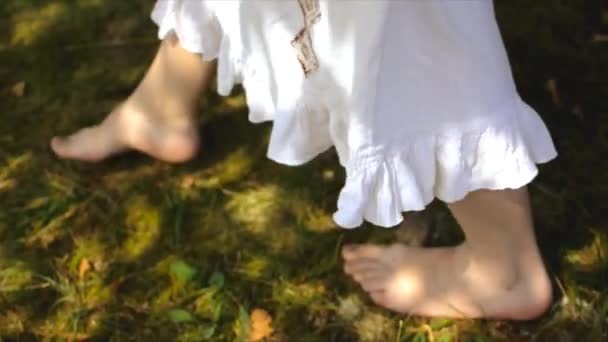 Młoda boso kobieta w białej etnicznej sukience w chodzenie po trawie — Wideo stockowe