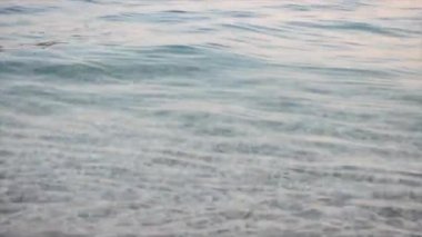 Deniz suyu yüzeyinin yakın çekim videosu. Dalgalar taştan bir kumsalda yuvarlanıyor