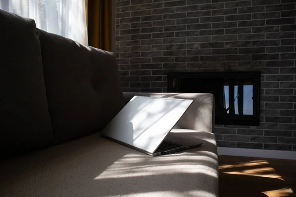 阳光灿烂的一天 笔记本电脑躺在沙发上 漂亮的现代内部与壁炉 没有人的概念 — 图库照片