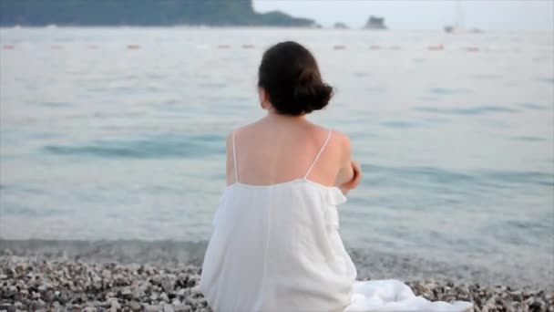 Mujer Joven Vestido Blanco Sentada Sola Playa Mirando Mar Tiempo — Vídeos de Stock