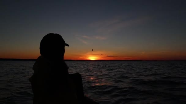 Silhouette einer jungen Frau, die irgendwo auf einem Boot im See sitzt — Stockvideo