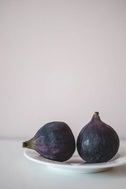 Taze taze incir minimalizmi. Gri arka plandaki tabakta sulu incirler. 