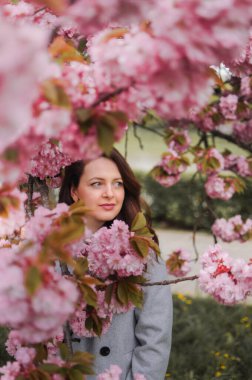 Baharda, pembe sakura ağacının yanında esmer bir kadın.