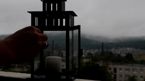 人类正在阳台上的灯笼中点燃一支蜡烛 多云的天空在恶劣的一天 — 图库视频影像