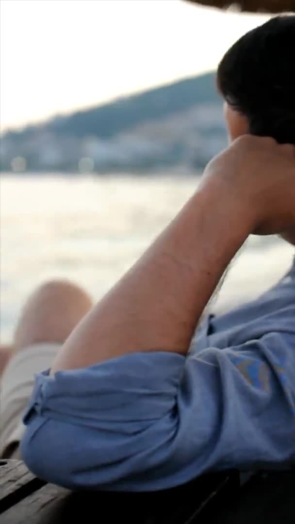 Скучающий Молодой Человек Сидящий Один Пляже Смотрящий Море Сумерках — стоковое видео