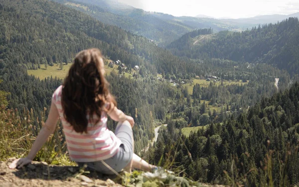 Arkadan genç bir kadın bir yaz günü dağ vadisine bakıyor.