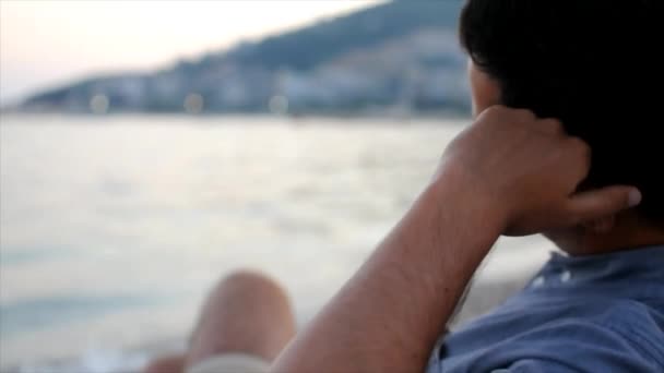 Joven Aburrido Sentado Solo Playa Mirando Mar Tiempo Twilling — Vídeos de Stock