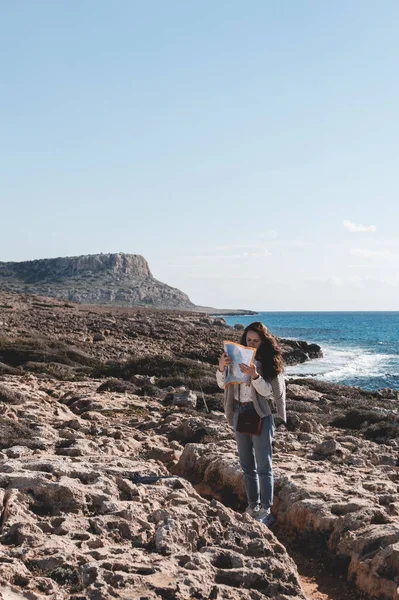 A young woman with a map is looking for a road to Cape Greco national park in Ayia Napa, Cyprus