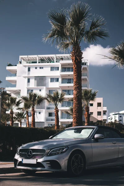 Kıbrıs 'ın Larnaka kentinde güneşli bir günde palmiye ağaçlarının önünde modern şık bir spor araba.. 