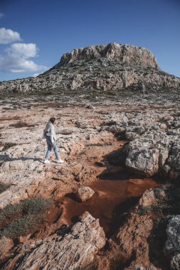 Genç bir kadın, Kıbrıs Rum Kesimi 'nin Ayia Napa kentindeki Cape Greco dağının önünde çölde yürüyor.. 