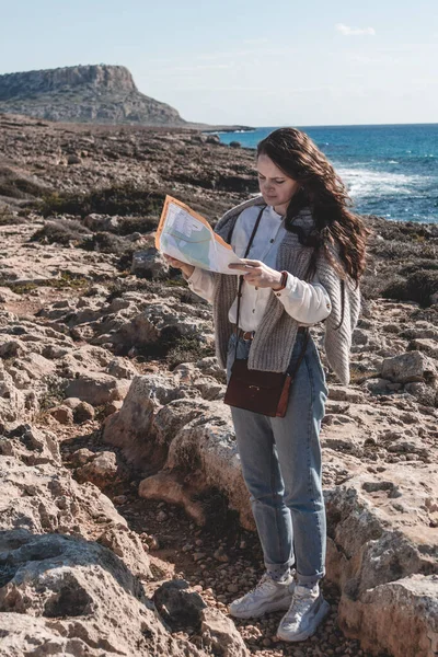 A young woman with a map is looking for a road to Cape Greco national park in Ayia Napa, Cyprus