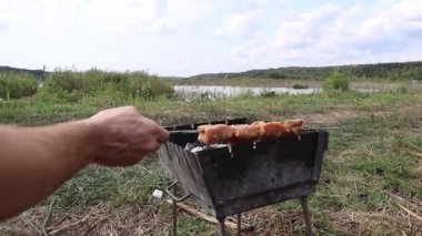 Adam çiğ tavuk etini dışarıdaki mangal şişine koyuyor.. 