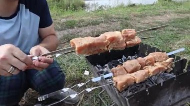 Adam çiğ tavuk etini dışarıdaki mangal şişine koyuyor.. 