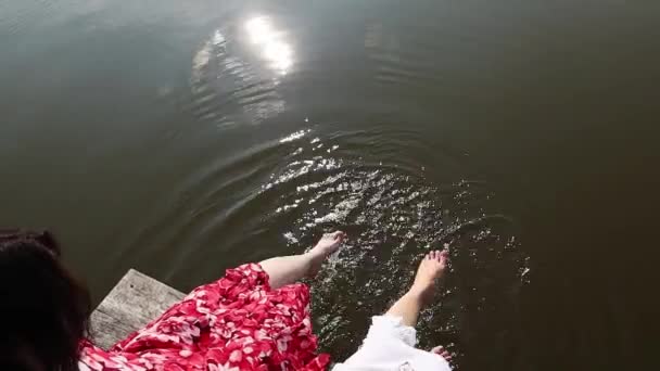 Two Barefoot Women Dress Waving Feet Lake Water While Sitting — Wideo stockowe