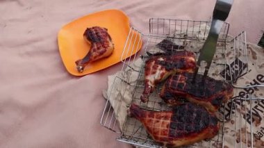 Man is putting chicken leg on a plate from a barbeque grid. 
