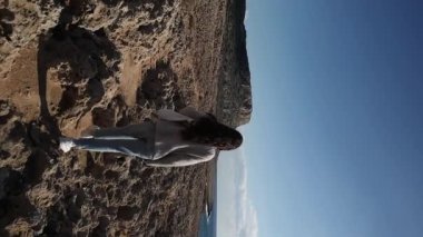 Arkadan genç bir kadın, Kıbrıs Rum Kesimi 'nin Ayia Napa kentindeki Cape Greco dağına doğru çölde yürüyor.. 