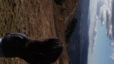 A young brunette woman is enjoying a mountains view. The girl is smiling on a beautiful sunny day in autumn