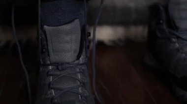 Person laces up hiking winter boots indoors. Close up of man put on trackers, and preparing himself 