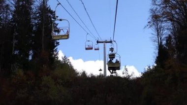 People are lifting up on a elevator in autumntime outdoors. Blue sky