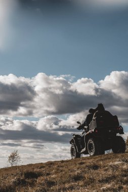 ATV 'deki insanlar güneşli bir günde dağlarda yoldan çıkıyorlar.