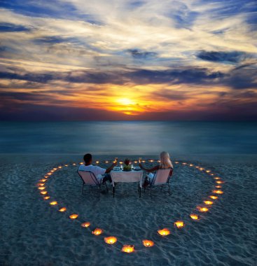 genç bir çift, kumsalda romantik bir akşam yemeği paylaşmak