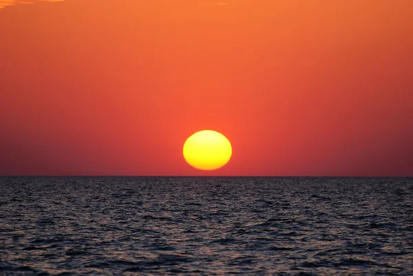 Ljusa solnedgången med stora gula solen under havet ytbehandlar — Stockfoto