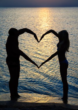 genç bir çift kalp plaj su karşı silah ile şekil verme