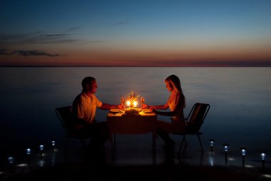 genç bir çift sahilde mum ile romantik bir akşam yemeği paylaşmak