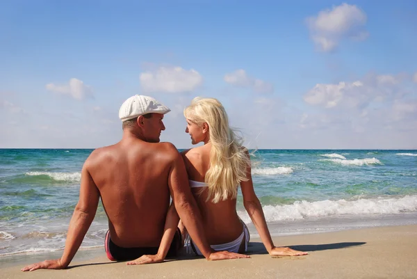 Casal amoroso sentado na praia de areia do mar e olhar para cada dente — Fotografia de Stock