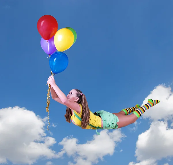 Joven chica bonita volar en globos de colores en el cielo azul — Foto de Stock